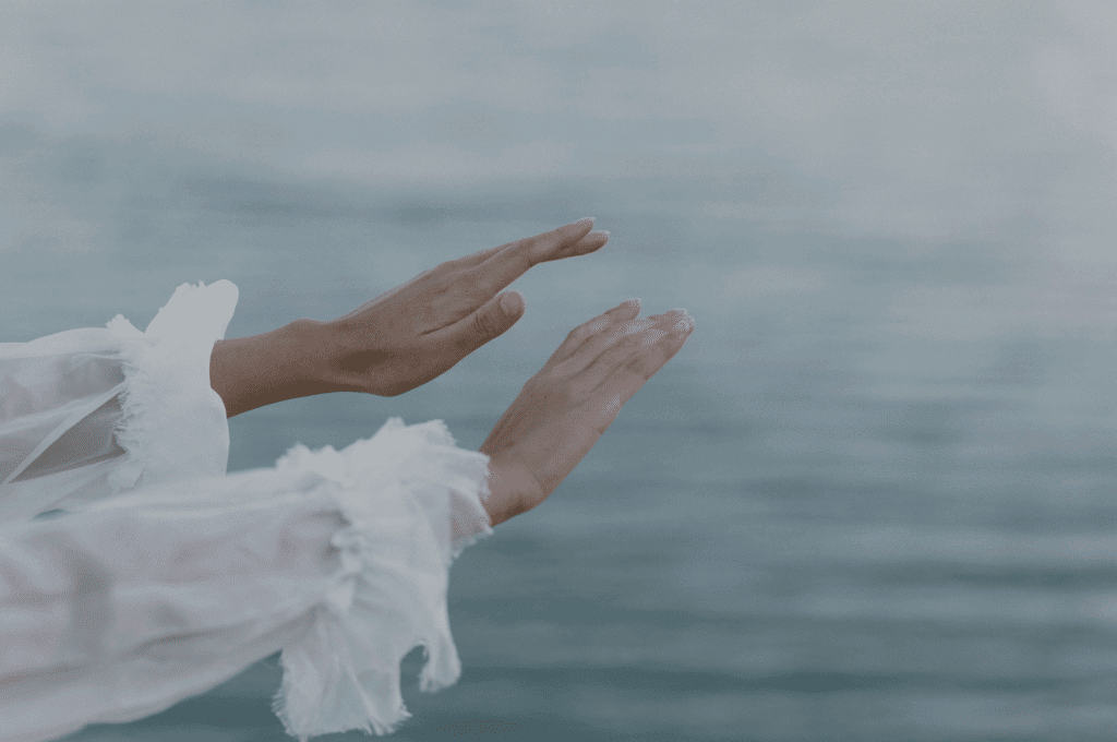 Ausgestreckte Hände über dem Meer – Symbol für Freiheit, Loslassen und Resilienz.