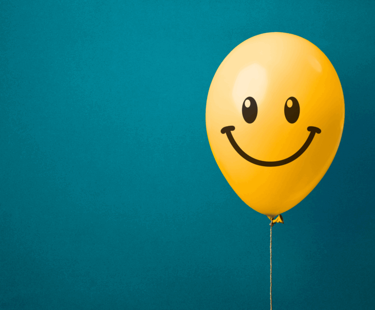 Gelber Smiley-Ballon vor blauem Hintergrund als Symbol für Glück und Lebensfreude – Mentaltraining Sandra Freidl