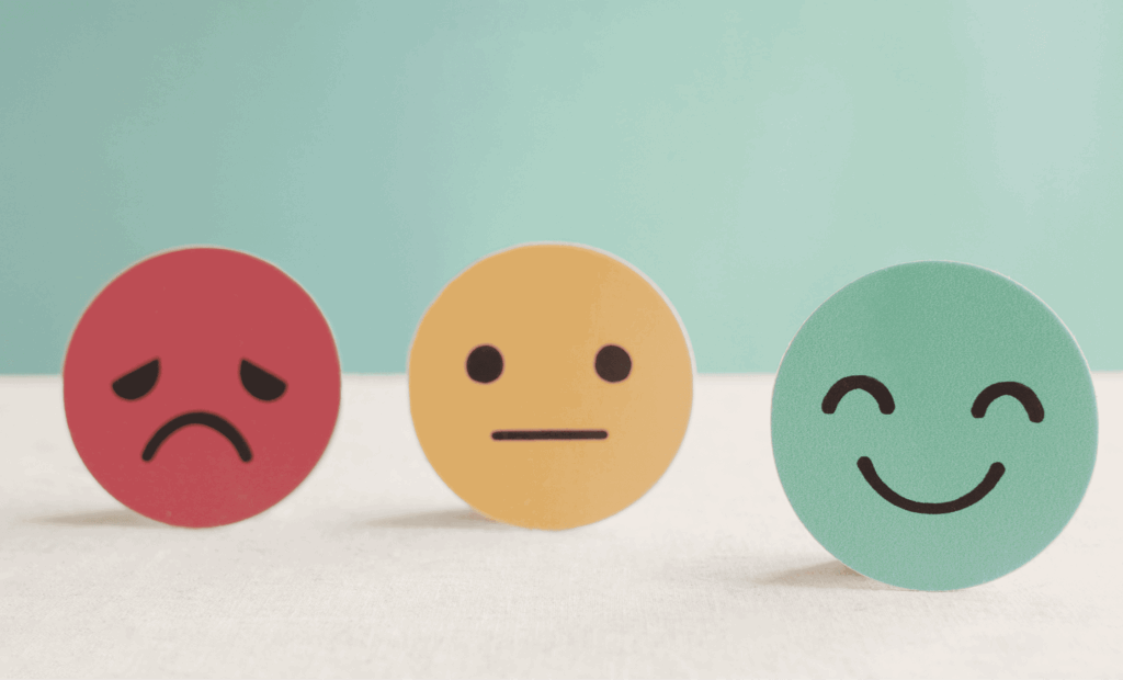 Drei Emojis mit unterschiedlichen Gesichtsausdrücken – traurig, neutral und glücklich – als Symbol für Emotionen und mentale Gesundheit.