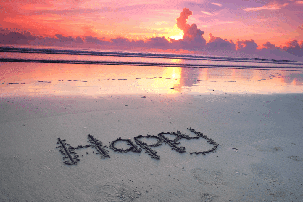 Glück am Strand: Schriftzug im Sand bei Sonnenuntergang – Symbol für innere Zufriedenheit