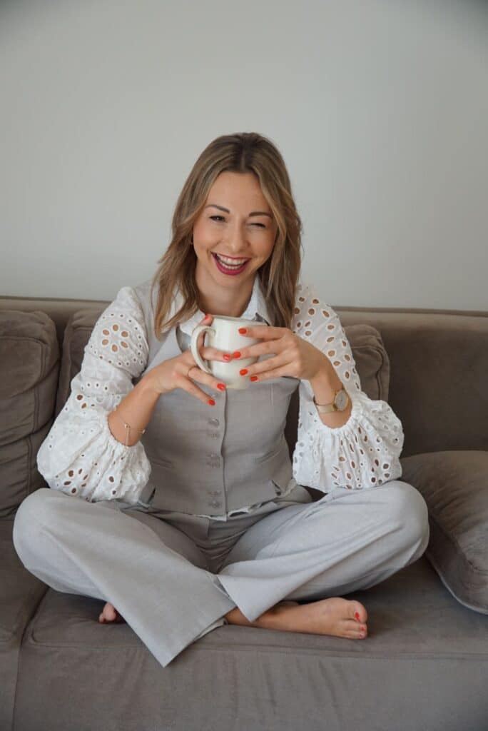 Frau sitzt im Schneidersitz auf dem Boden und formt mit den Händen ein Herz – Symbol für Selbstliebe, mentale Gesundheit und persönliche Entwicklung