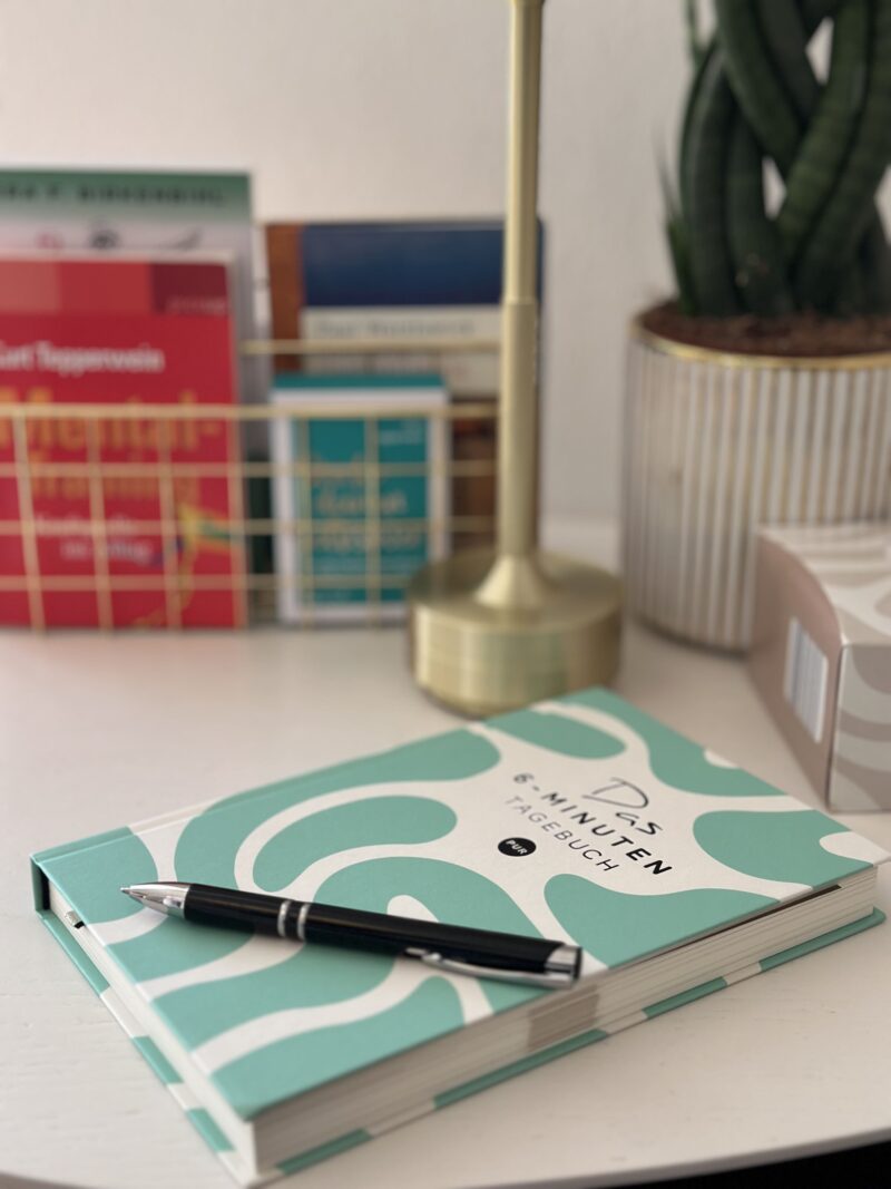 Bücherstapel mit Notizbuch und Brille auf einem Tisch – Symbolbild für persönliche Weiterentwicklung, Lesen und mentale Gesundheit