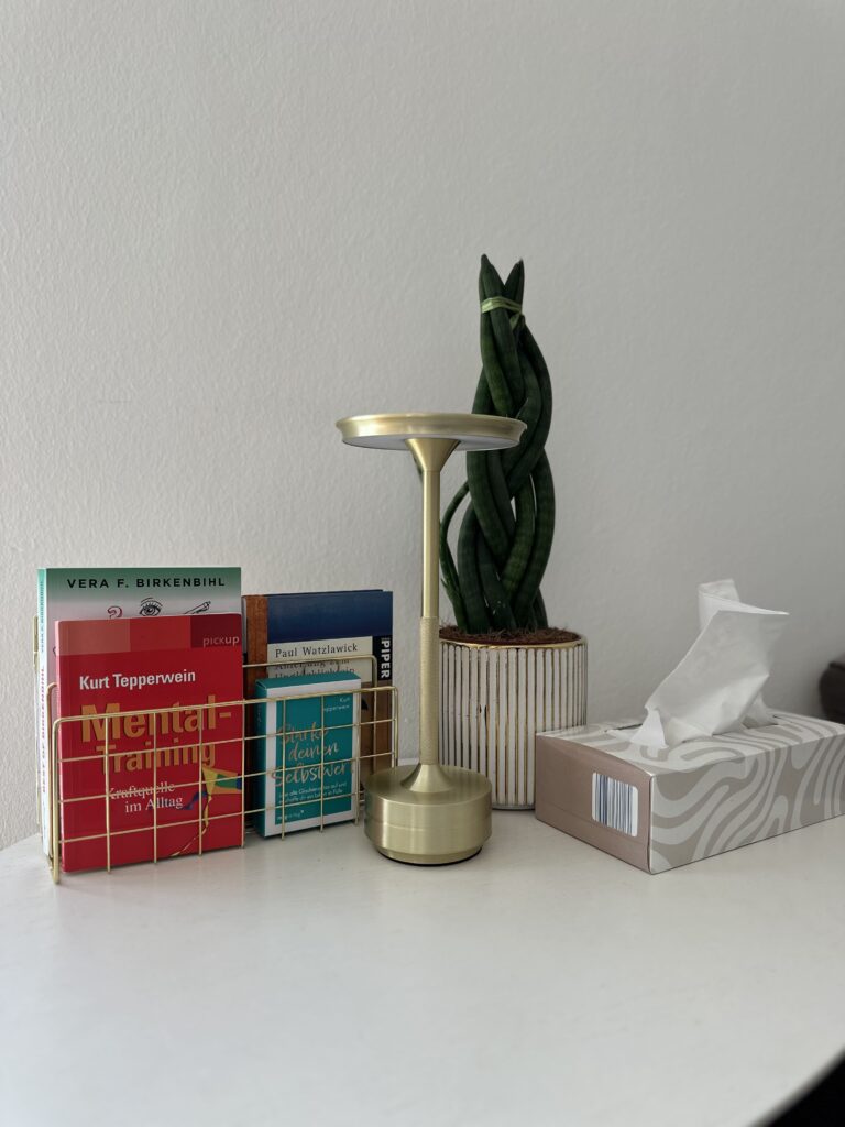 Mentaltraining Graz – ruhiger Arbeitsplatz mit Büchern, Pflanze und Kerze für mentale Klarheit