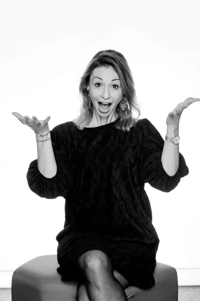 Sandra Freidl sitzt lachend mit ausgebreiteten Armen – energiegeladen und authentisch steht sie für mentale Klarheit